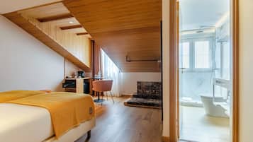 Un dormitorio con cama, escritorio, silla y vistas al baño.