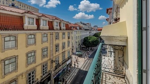 Una calle estrecha flanqueada por edificios, cielo despejado y algunos peatones.