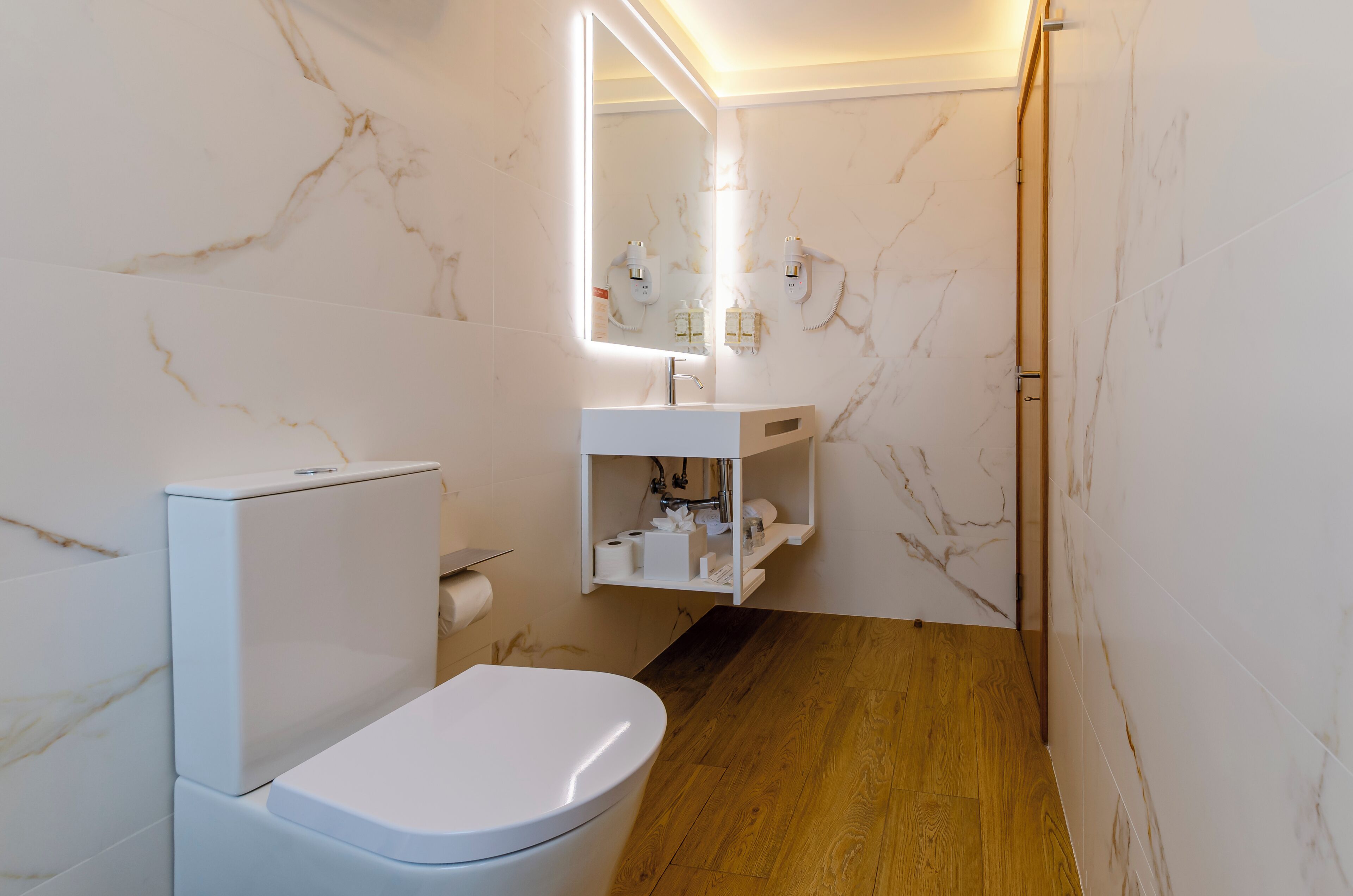 Een moderne badkamer met toilet, wastafel en spiegel.