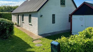 Une maison de plain-pied avec un toit en pente, un petit garage attenant et une pelouse bien entretenue.