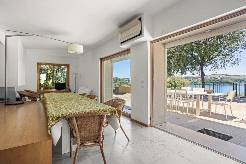 Una habitación moderna con una mesa de comedor, sillas, un televisor y un amplio ventanal con vistas a un paisaje idílico.