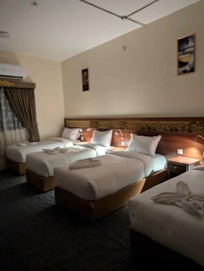 Quarto de hotel com duas camas, mesa de cabeceira, abajur e um quadro na parede.