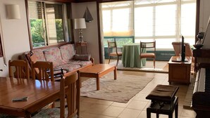 Ein großzügiges Wohnzimmer mit Essbereich, einem Klavier und einer großen Schiebeglastür, die auf einen Balkon führt.