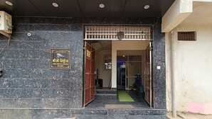 A building entrance with a sign, steps leading to a door, and a visible interior space. - Hotel Shriji Nikunj (Mathura)