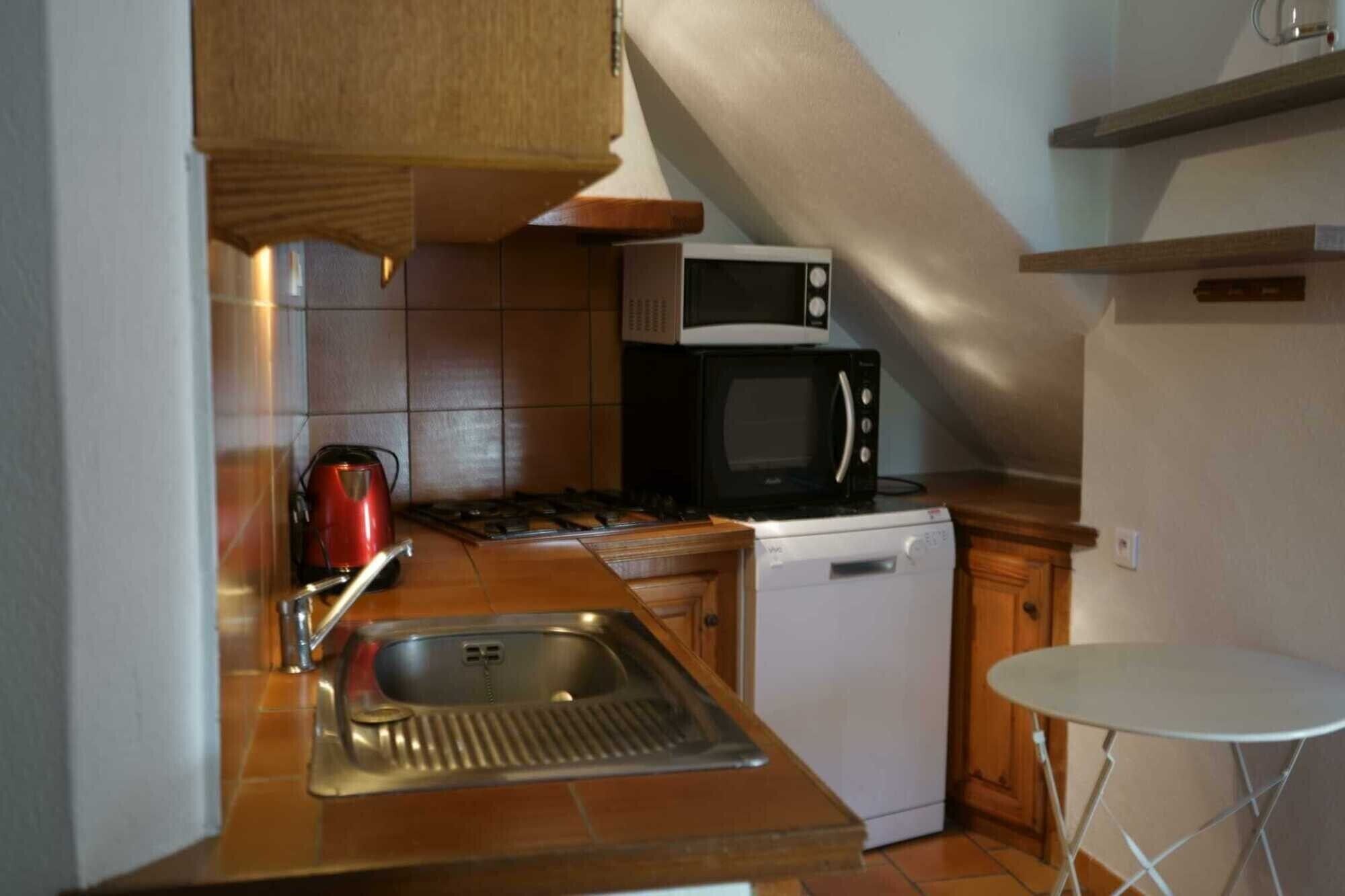 A compact kitchen with a sink, stove, microwave, and dishwasher.