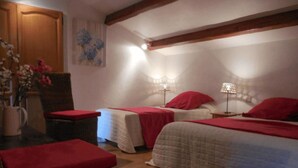 A room with two beds, a wicker chair, a wooden door, and a wall with a floral painting. - Holiday Home 'La Bergerie' with Shared Pool, Private Terrace and Wi-Fi (Fontarèches)
