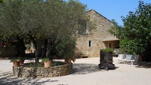 A stone building with a sloped roof, surrounded by trees and potted plants. - Holiday Home 'La Bergerie' with Shared Pool, Private Terrace and Wi-Fi (Fontarèches)