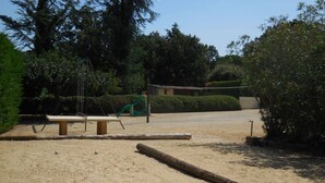 A sandy outdoor area with a swing set, a bench, and a wooden log. - Holiday Home 'La Bergerie' with Shared Pool, Private Terrace and Wi-Fi (Fontarèches)