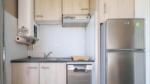 Een moderne keuken met houten kastjes, een roestvrijstalen koelkast, een inbouwvaatwasser en een bordje van een koffiezaak.