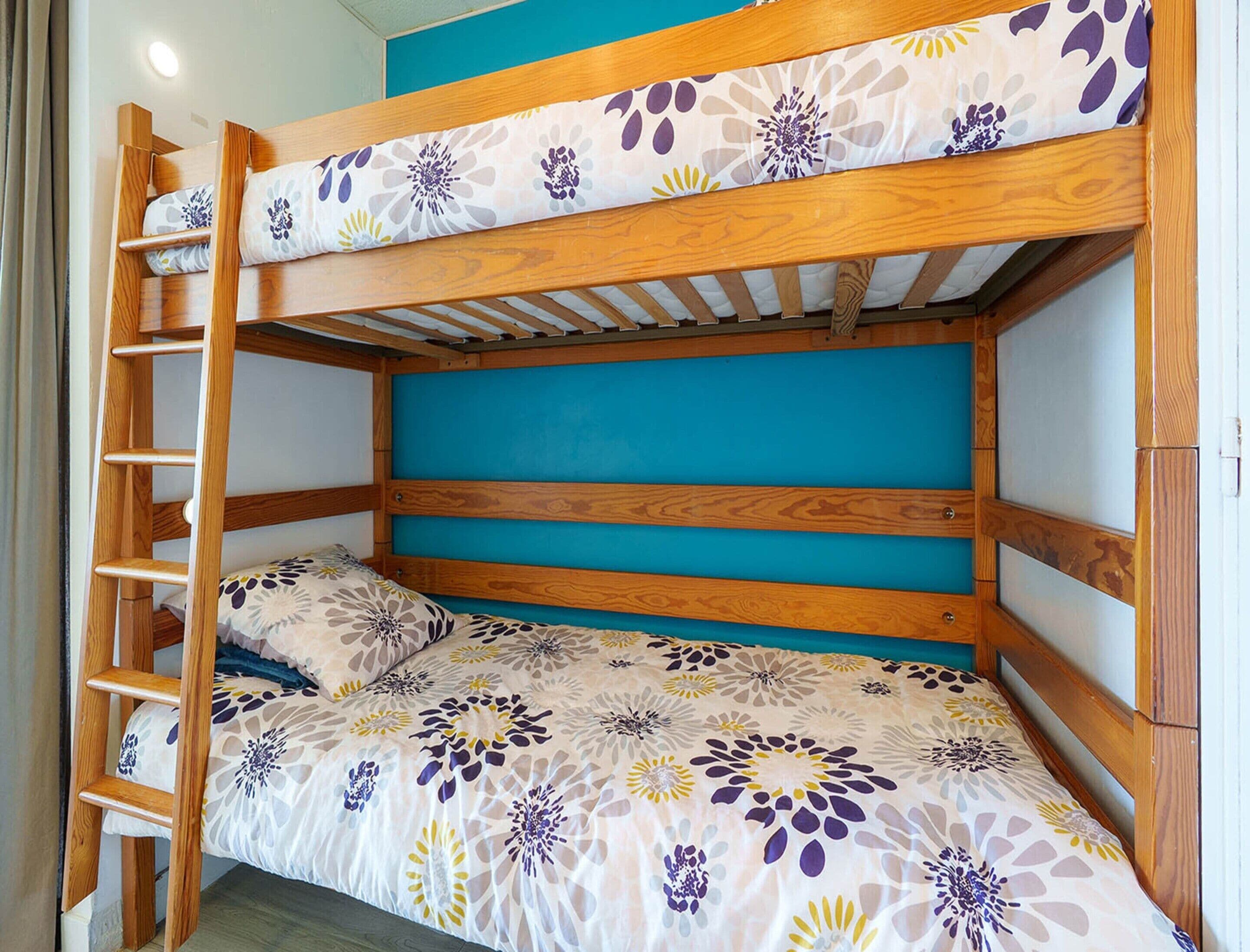 Un letto a castello con struttura in legno e testiera blu.