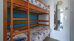 Een stapelbed met bloemenbeddengoed, een deur met een spiegel en een blauwe wand.