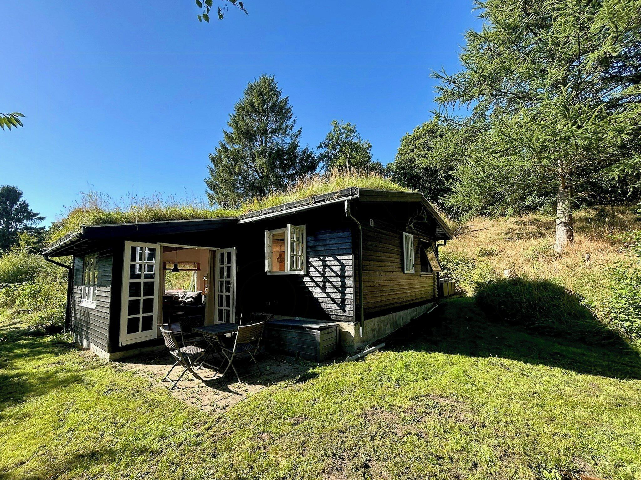 En lille hytte med veranda, spisebord og stole.