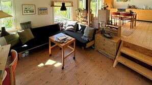 Ein gemütliches Wohnzimmer mit einer Couch, einem Holztisch und einem Essbereich mit Stühlen und Tisch.