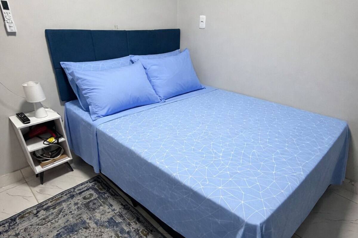 A bedroom with a bed, a nightstand, a lamp, and a patterned rug.