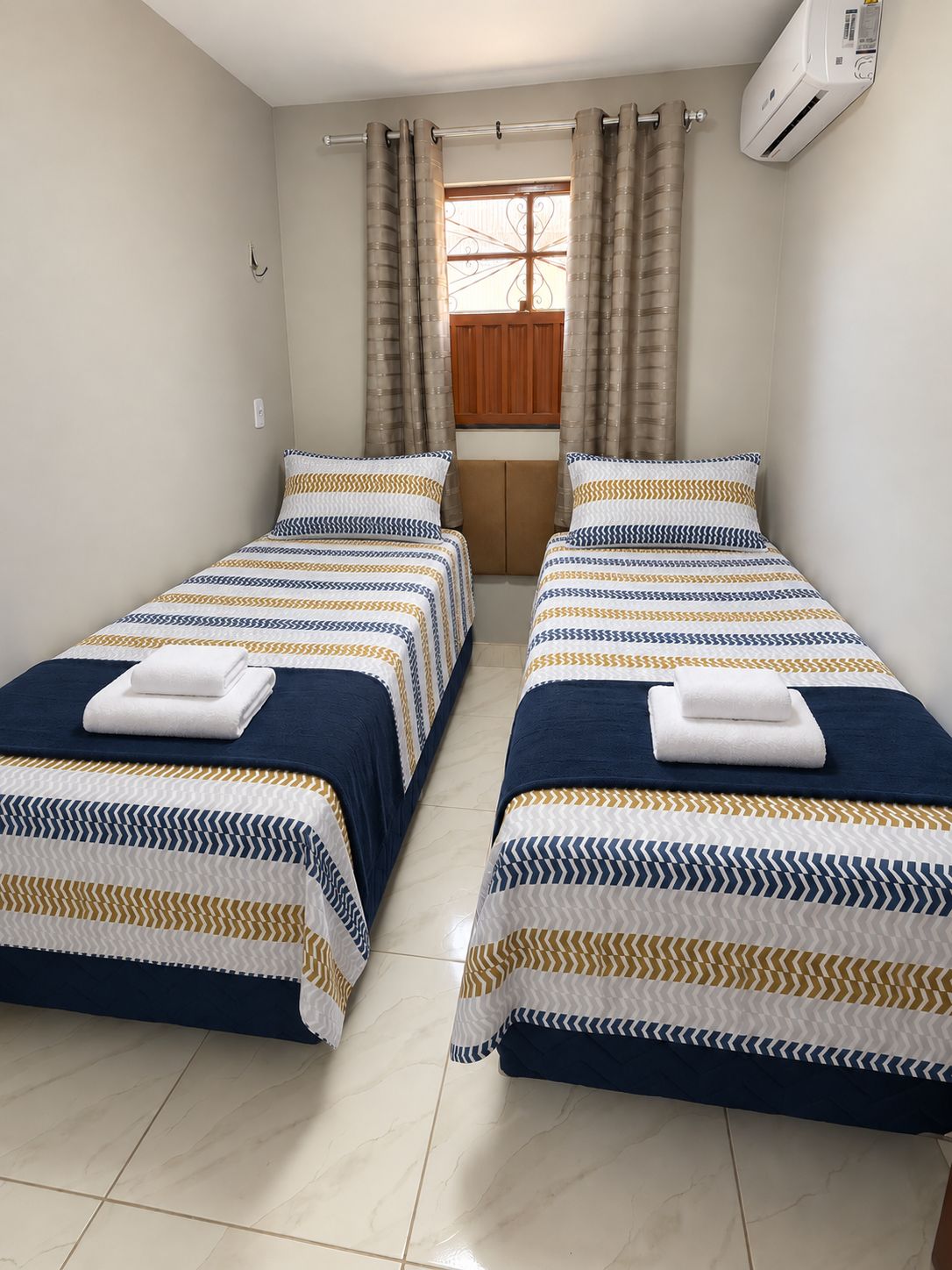 Habitación de hotel con dos camas, cada una con ropa de cama y toallas a rayas.