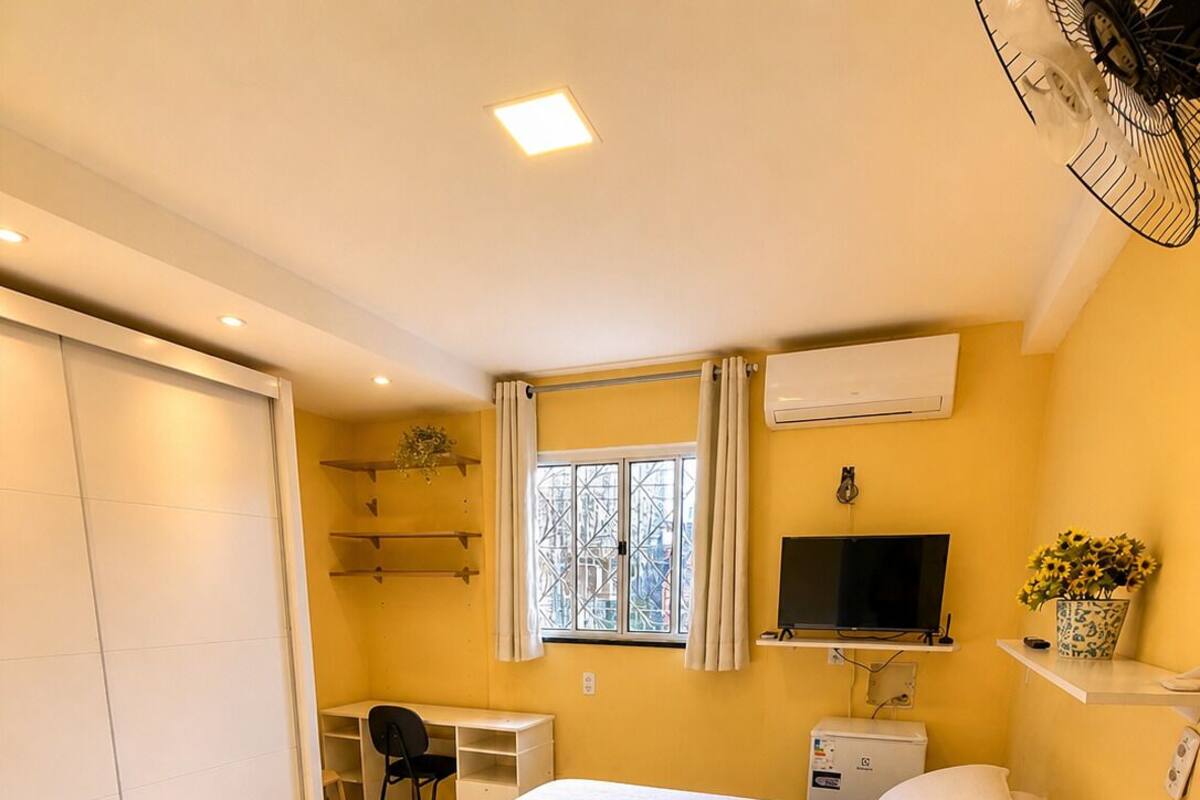A hotel room with a bed, a desk, a chair, a TV, and a window with curtains.