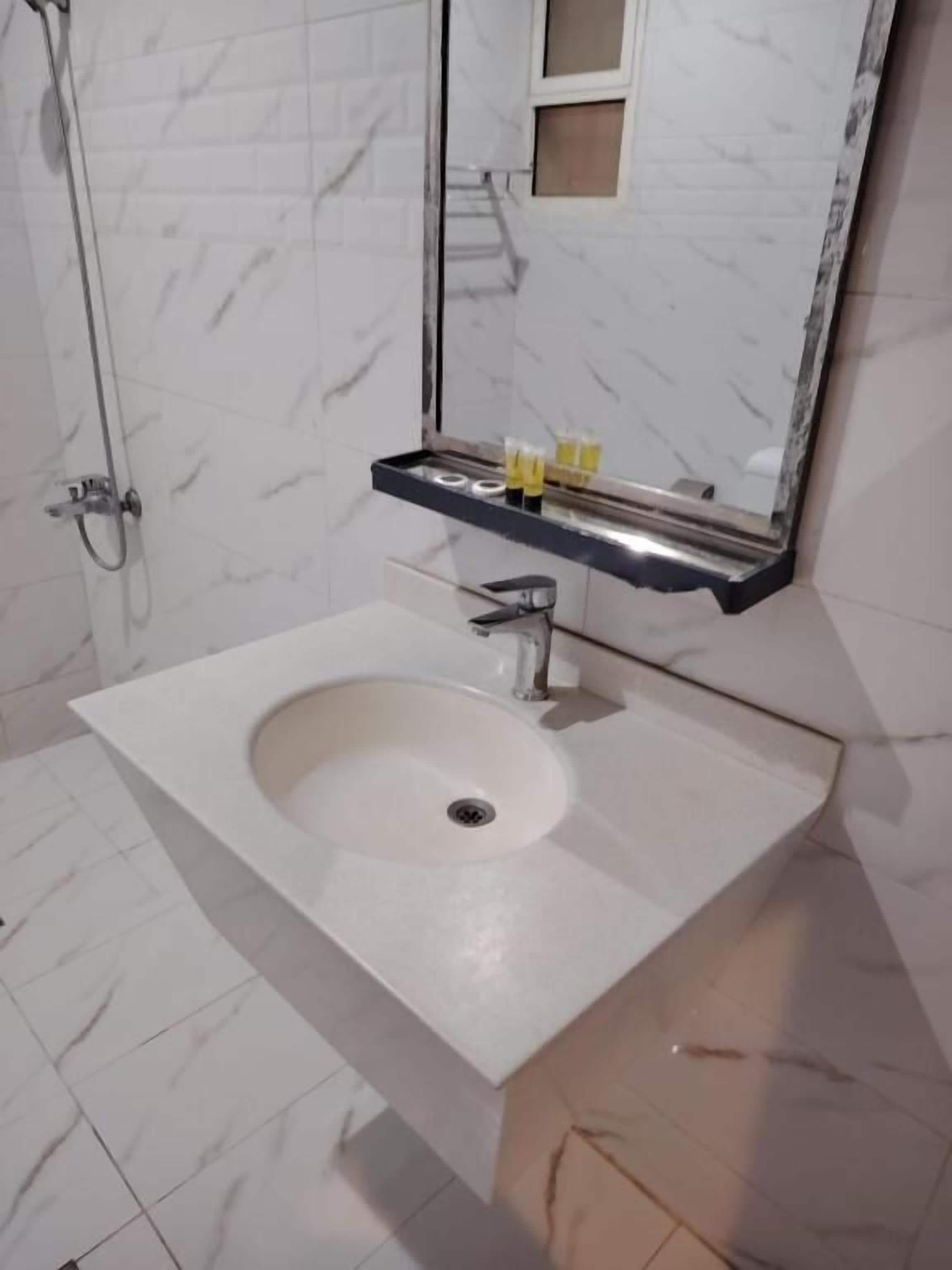 Un baño con un lavabo blanco, un espejo y una ducha.