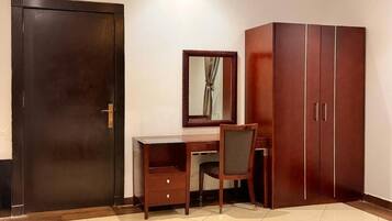 A room with a desk, chair, wardrobe, and a mirror.