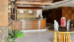 A reception area with a wooden reception desk, a round table with a yellow base, and a potted plant. - Quiet Rooms 12   (Riyadh)