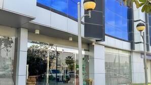 A modern building with a glass facade, a covered entrance, and a street lamp. - Quiet Rooms 12   (Riyadh)