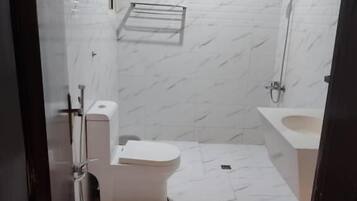 Un baño con inodoro, ducha y lavamanos, todo con un diseño moderno.