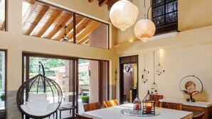 A dining area with a wooden ceiling, hanging light fixtures, and a hanging chair. - Casa Avándaro (Valle de Bravo)