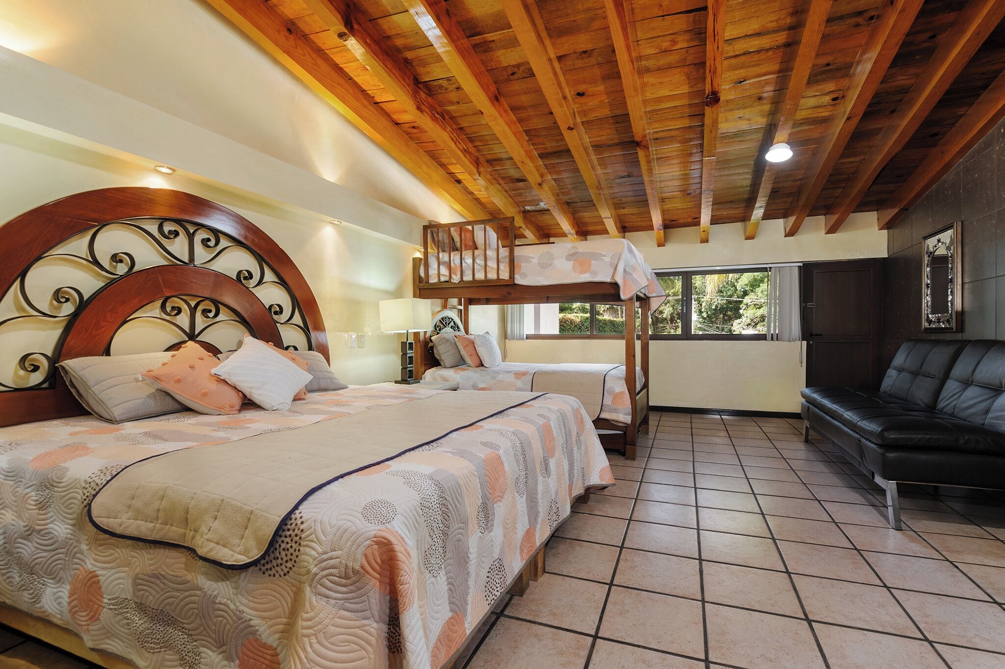 Una camera da letto con due letti, un letto a castello, una comoda divisa in pelle nera e una grande finestra.
