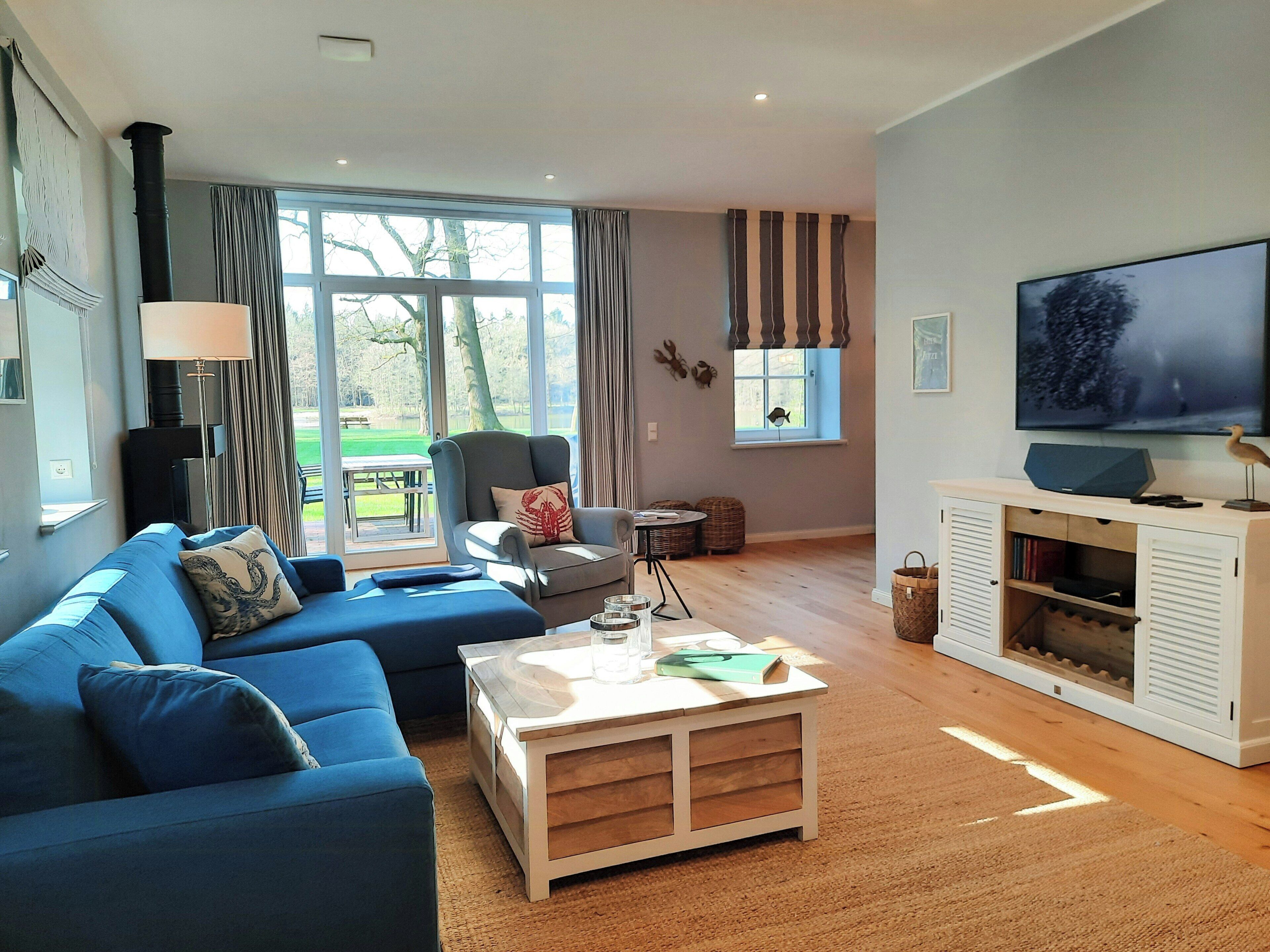 Una sala de estar con sofá, mesa de centro, televisor y vistas al exterior.