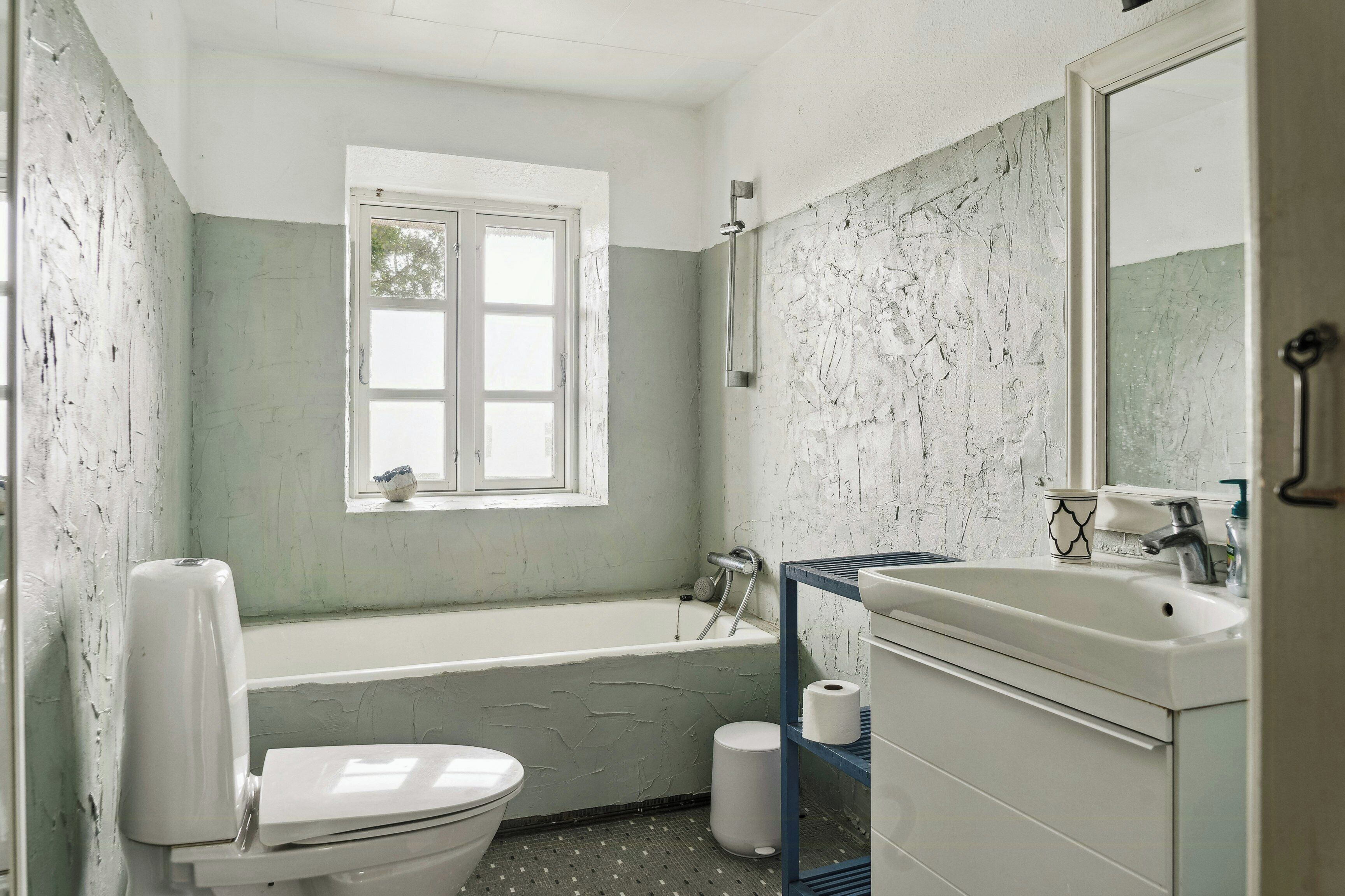 Un baño con bañera, inodoro, lavabo y ventana.