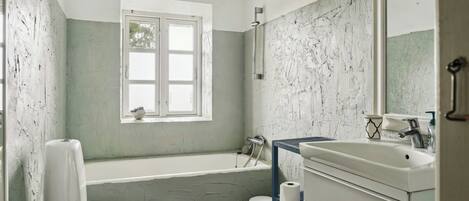 Un baño con bañera, inodoro, lavabo y ventana.