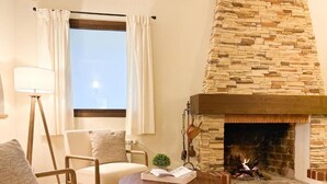A living room with a stone fireplace, a sofa, a coffee table, and a lamp.
