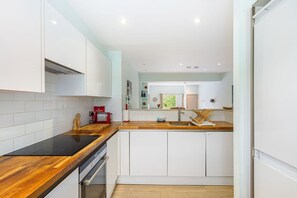 Eine moderne Küche mit weißen Schränken, einer Holz Arbeitsplatte und einem eingebauten Backofen.