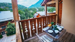 A balcony with a table set for dining, overlooking a mountainous landscape. - Studio for 4 Near Pyrenees Ski Slopes (Ax-les-Thermes)