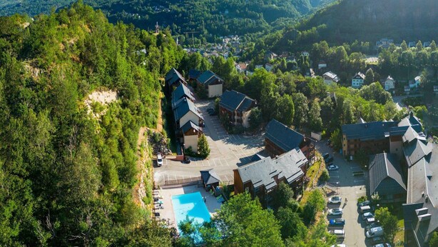 A resort with multiple buildings, a swimming pool, and a mountainous backdrop. - Studio for 4 Near Pyrenees Ski Slopes (Ax-les-Thermes)