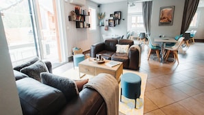A modern living room with a sofa, coffee table, and dining area with chairs. - Studio for 4 Near Pyrenees Ski Slopes (Ax-les-Thermes)