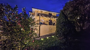 Ein Gebäude mit Balkon, umgeben von Grünpflanzen und Lichterketten.