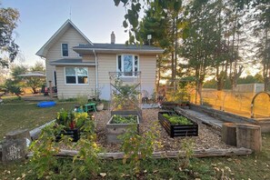 Une maison avec un jardin, du mobilier d’extérieur et une piscine bleue.