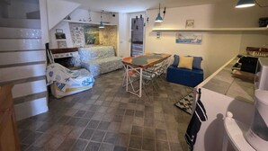 A compact living space with a dining area, a sofa, a small kitchen, and a staircase. - La Casa Bianca nel Borgo - by Be Your Home (San Felice Circeo)