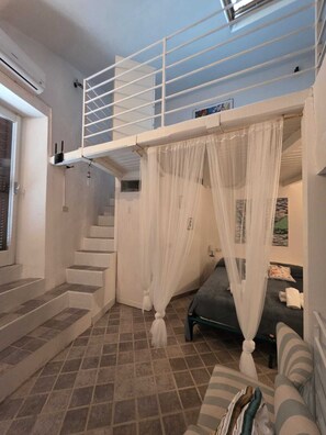 A room with a bunk bed, a staircase, a couch, and a bed.