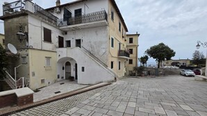 A building with a staircase leading to an entrance, a paved courtyard, and a view of the sea. - La Casa Bianca nel Borgo - by Be Your Home (San Felice Circeo)