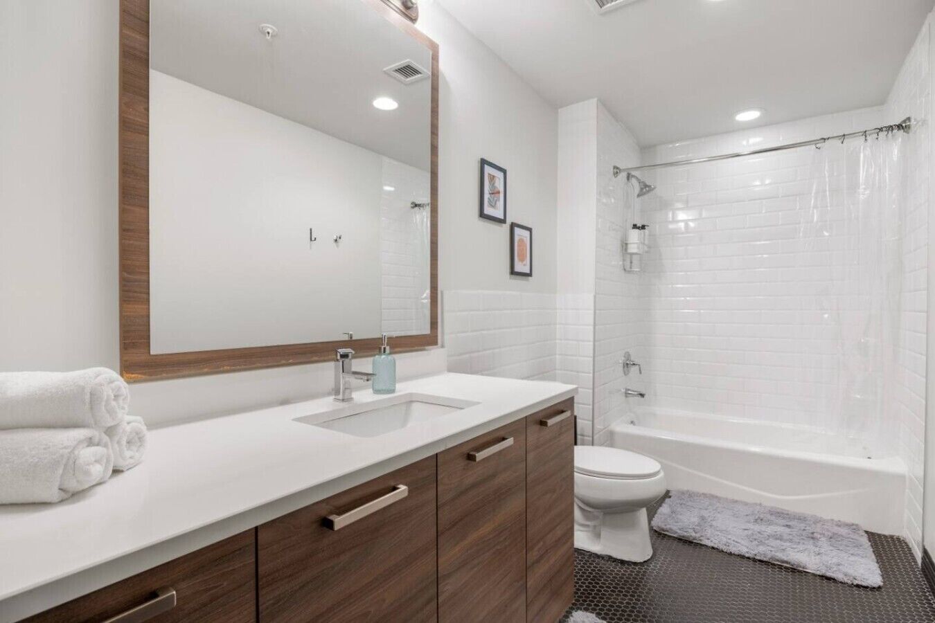 Un baño moderno con lavamanos, tocador y bañera blancos.