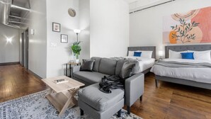 Une pièce moderne et bien éclairée, avec un canapé, un lit, une table basse et une plante.
