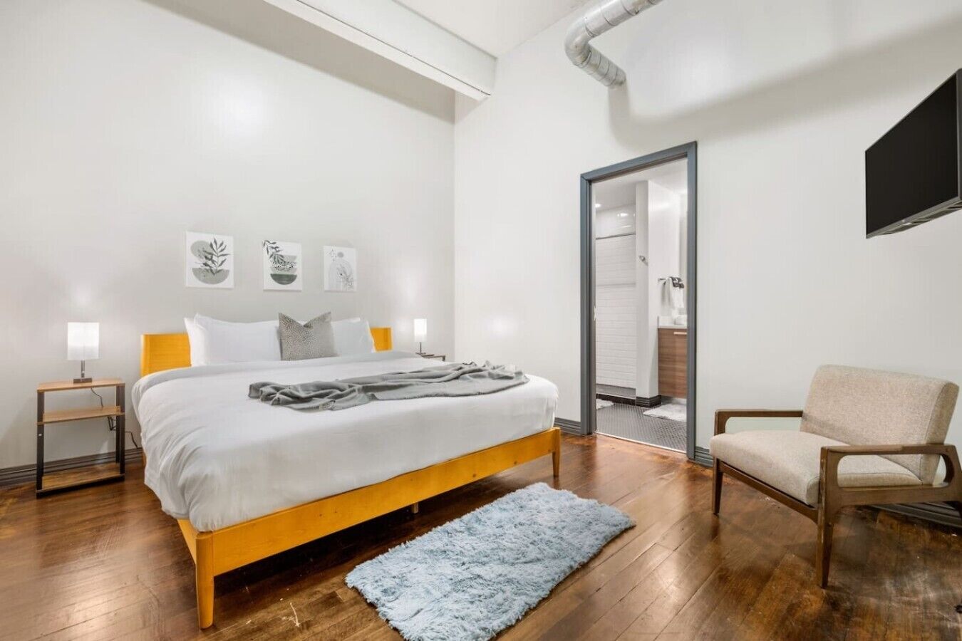 Een moderne slaapkamer met een bed, nachtkastjes, een stoel en een spiegel.