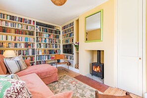 Ein gemütliches Wohnzimmer mit Kamin, Bücherregal und einer bequemen Sitzecke.