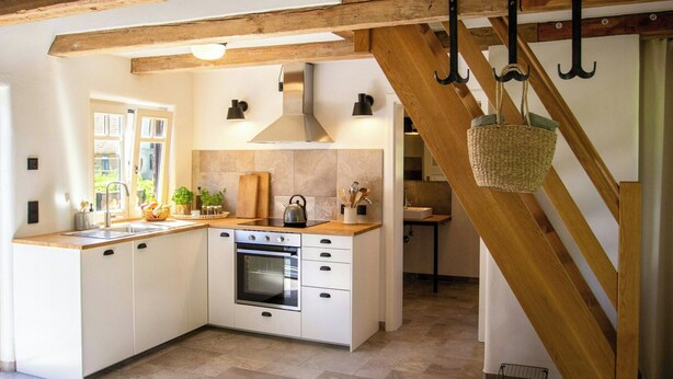 A kitchen with white cabinets, a stove, and a hanging basket. - Oasis of peace near the lake (Langen Jarchow)