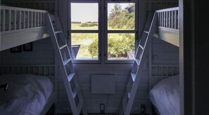 A dormitory room with bunk beds, a window, and a ladder. - Wake up with water views from Omø (Omø)