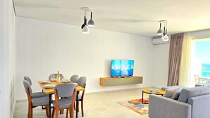 Een moderne woonkamer met een eethoek, een flatscreen televisie en een bank.