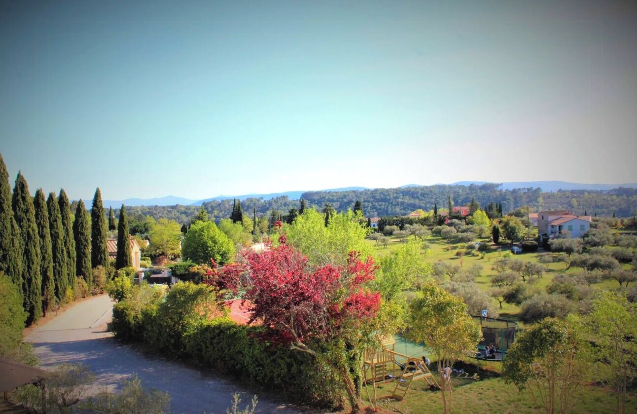 Paisatge rural amb cel blau, arbres i alguns edificis.