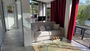 Ein Wohnzimmer mit einer Couch, einem Glastisch und Blick ins Freie.