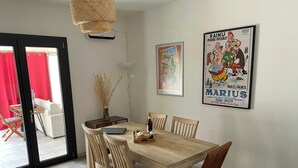 Ein Essbereich mit einem Holztisch, Stühlen, einer Vase mit getrockneten Pflanzen und zwei gerahmten Postern an der Wand.